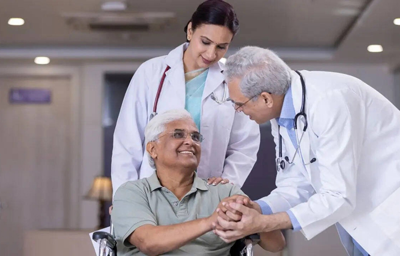 Doctors comforting disabled elderly patient at hospital