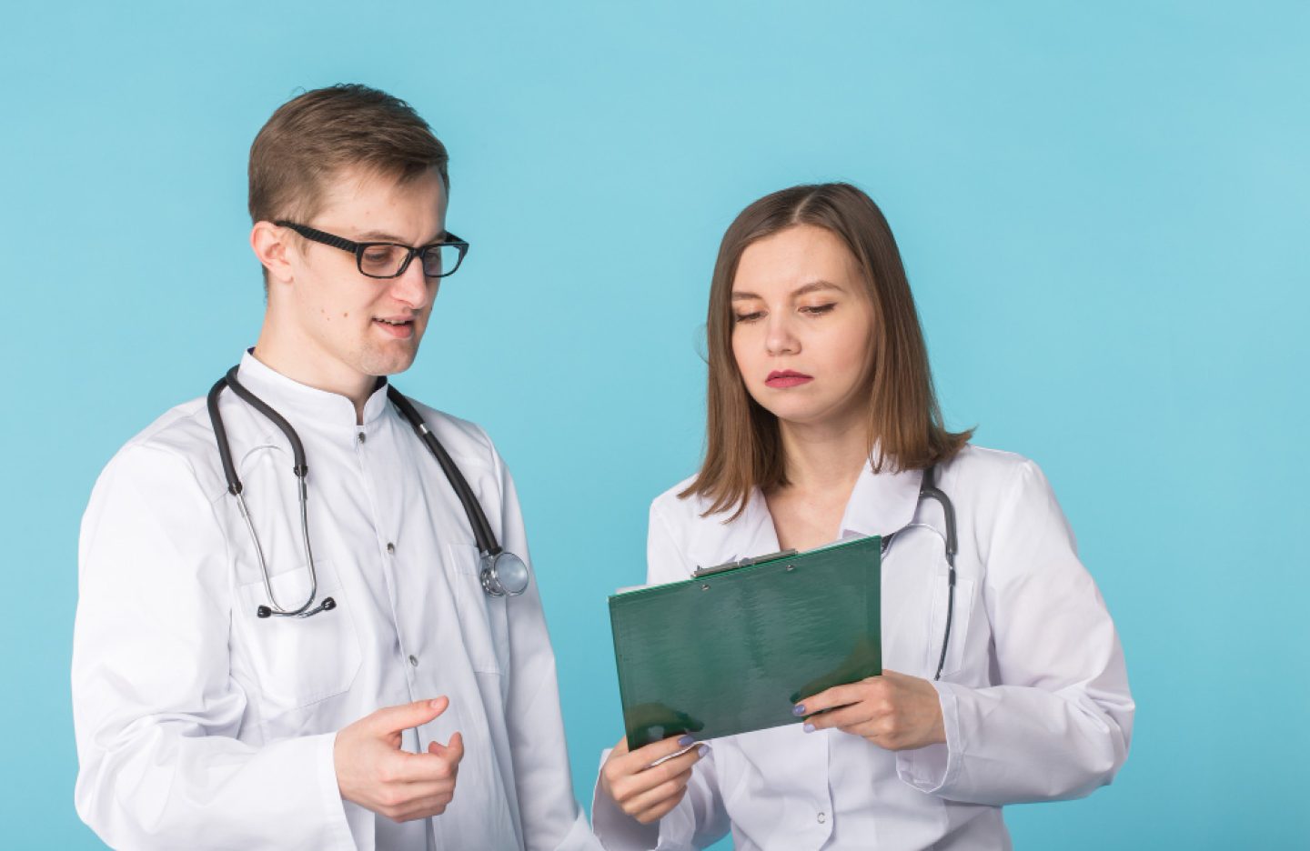 young-male-female-doctors-discussing-blue-background (1)