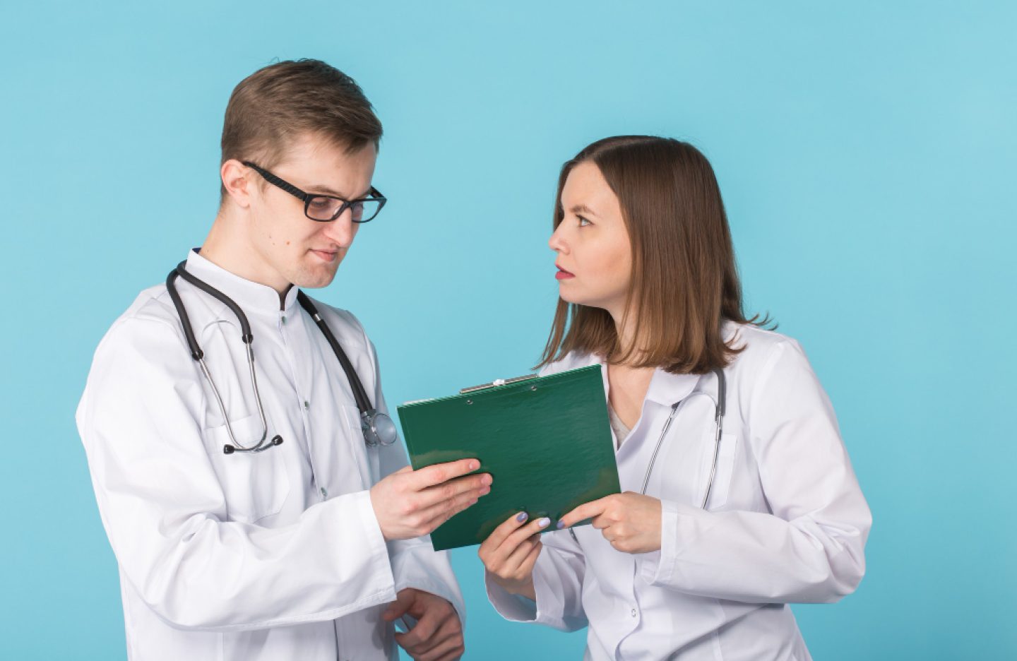 young-male-female-doctors-discussing-blue-background